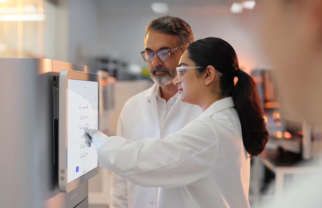 Profile image of male and female scientists reviewing the run setup screen, in the foreground a female scientist is holding a 1.5 reagent in her hands.